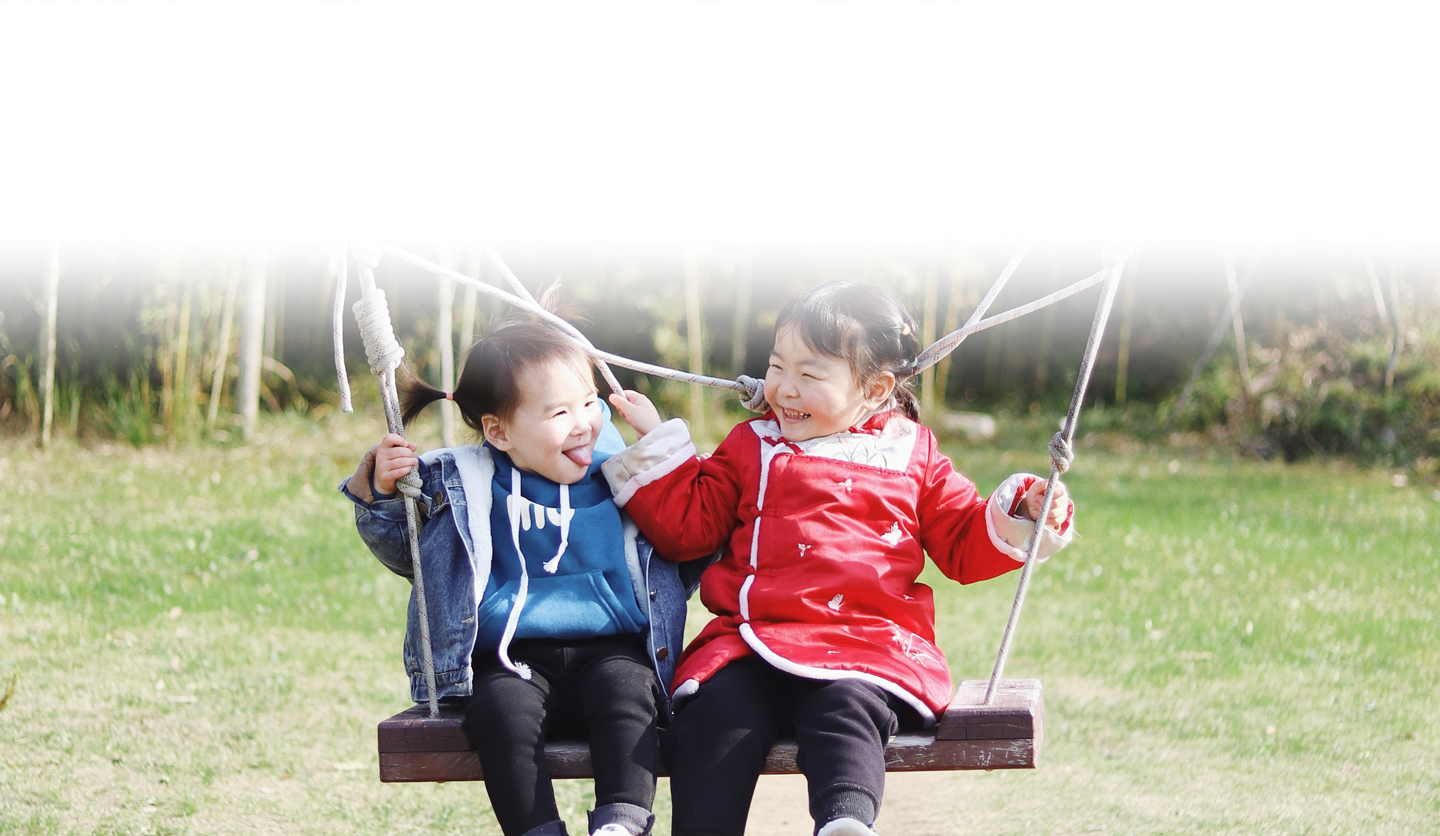 Two kids playing on a swing together