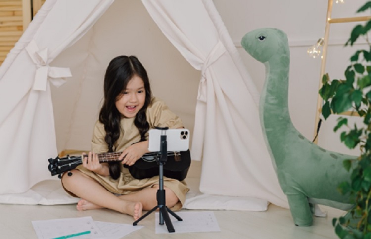 Young girl plays guitar as she reads music