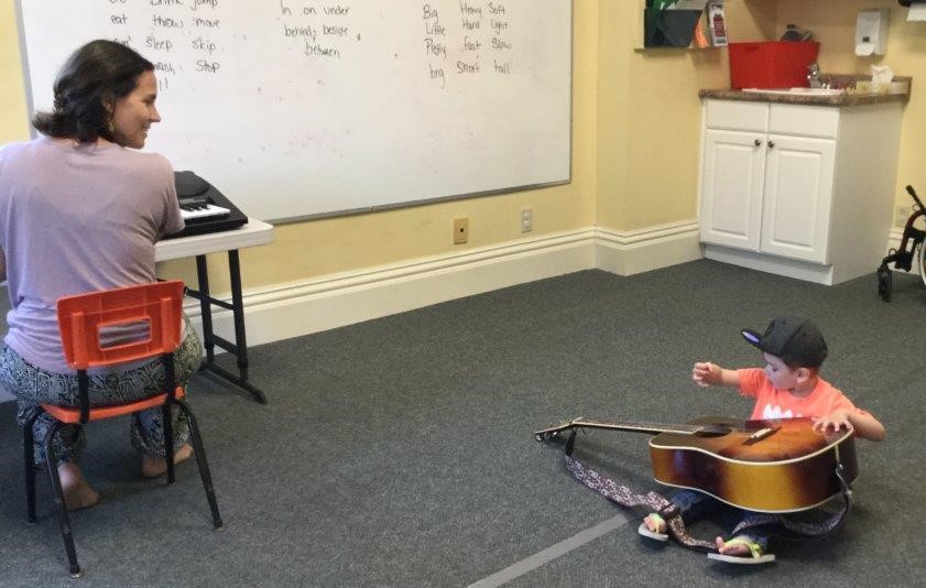 Child playing guitar during music therapy session